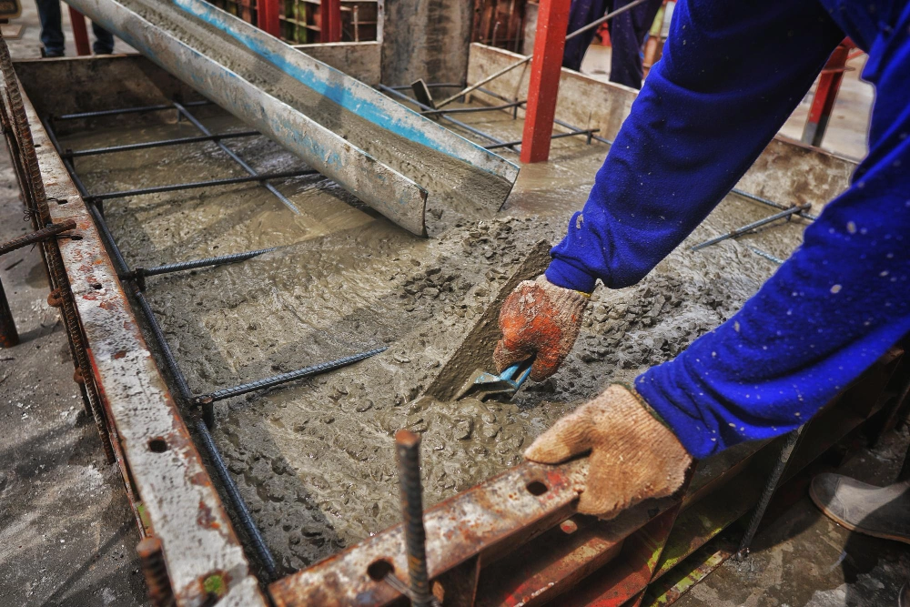 worker reinforcing concrete retaining wall with steel and proper drainage setup