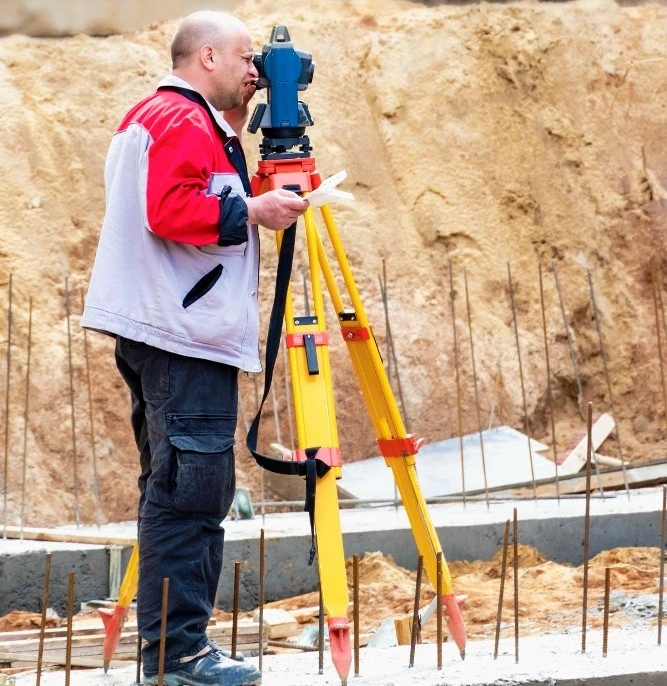 site inspector using a surveying tripod to assess ground levels in Los Angeles